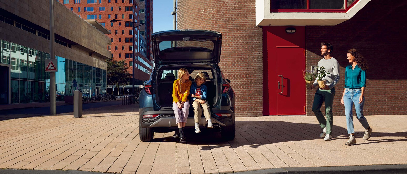 Hyundai familiebil holdende TUCSON i byområde med åben bagagerum