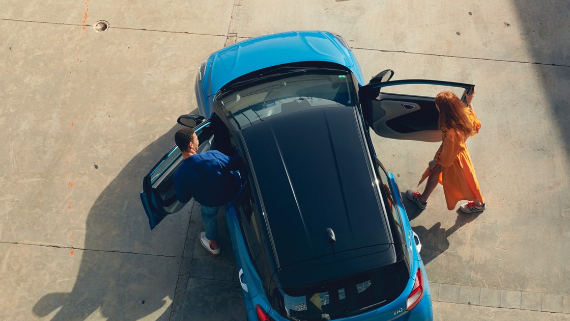 Mand og kvinde på vej ind i en Aqua Turquoise Hyundai i10 set fra luften