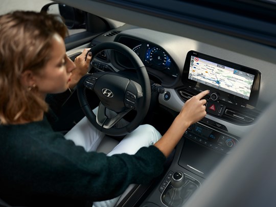 Kvinde trykker på navigationssystemet på 10,25" i en Hyundai i30 stationcar 